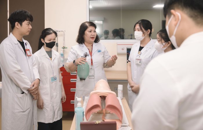 Group of medical students practicing skills with a training mannequin in a classroom setting.