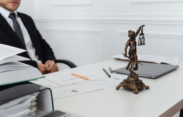 A legal professional's workspace featuring Lady Justice statue, documents, and a laptop.