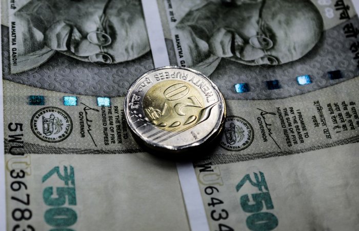 Close-up image of Indian rupee notes with a twenty rupee coin, illustrating financial themes.