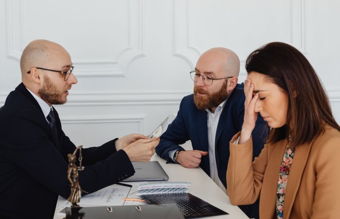 Lawyer discussing divorce settlement with distressed couple during tense meeting.