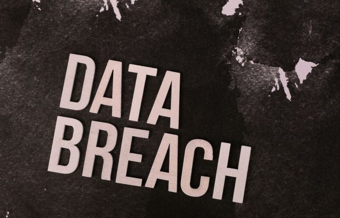 A conceptual image highlighting the issue of data breaches, featuring bold text on a textured background.