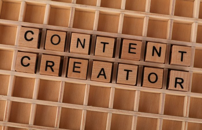 Wooden block letters spelling 'Content Creator' on a grid background. Ideal for digital marketing themes.