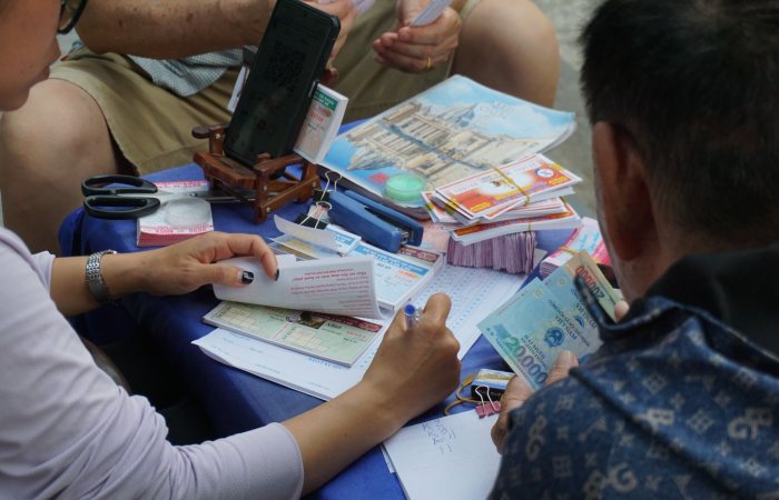 Casual gathering playing lottery outdoors in Ha Giang, Vietnam, capturing cultural street life.