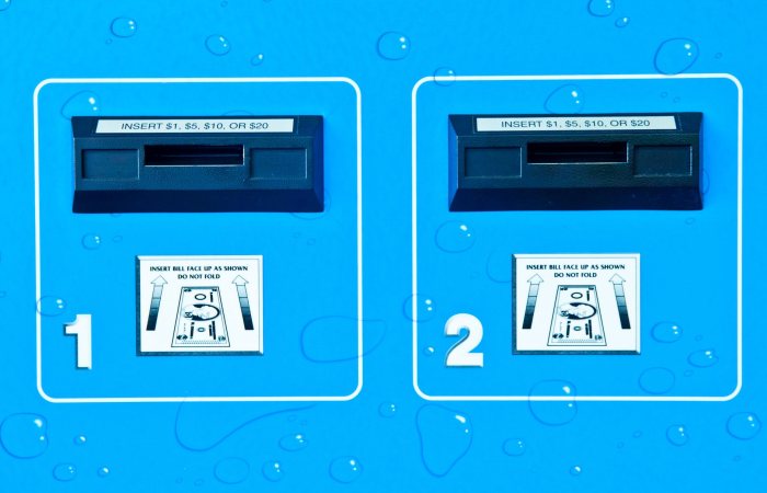Close-up view of vending machine bill acceptors with payment instructions on a blue background.