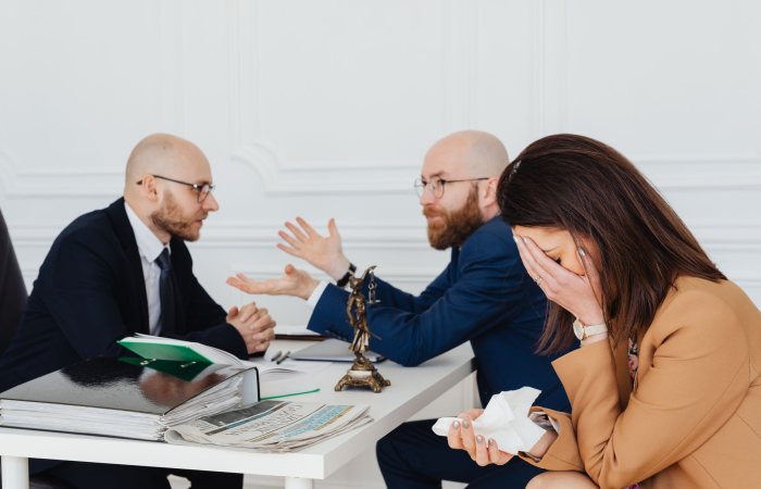 A lawyer mediates an emotional settlement discussion with a distressed couple in a legal office.